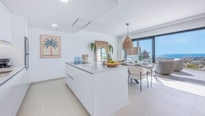 A modern kitchen with a large island, white cabinetry, and a view of the ocean. - NEW!!! Sea Views, Beach, Pools, and Golf at La Cala Mijas—One Heights Apartment (Mijas)