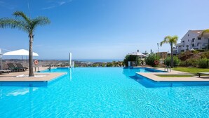 A clear blue swimming pool with a lifebuoy, lounge chairs, and umbrellas. - NEW!!! Sea Views, Beach, Pools, and Golf at La Cala Mijas—One Heights Apartment (Mijas)