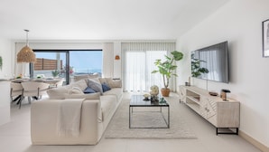 A modern living room with a sofa, coffee table, TV, and a dining area with a table and chairs. - NEW!!! Sea Views, Beach, Pools, and Golf at La Cala Mijas—One Heights Apartment (Mijas)