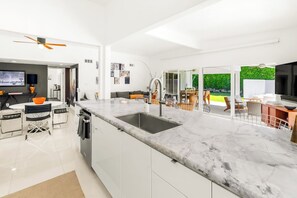 A modern kitchen with a marble countertop, integrated sink, and a dining area with a table and chairs. - 25% Off Sept 11-13 Great 4 Families -Pool, Jacuzzi (Palm Springs)