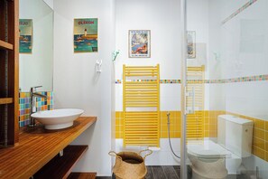 A bathroom with a wooden vanity, a white sink, a yellow towel rack, and a shower with a glass door. - Villa La Gabelle (Saint-Georges-d'Oléron)