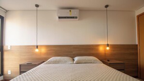 Ein modernes Schlafzimmer mit einem hölzernen Kopfteil, einer zentralen Klimaanlage und zwei Nachttischlampen.