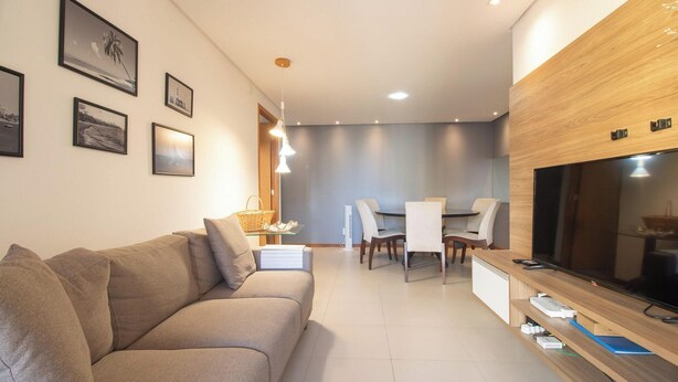 Ein modernes Wohnzimmer mit einer Couch, einem Essbereich mit Stühlen und einem Tisch sowie einem Fernseher auf einem Holzboden.
