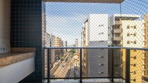 Ein Balkon mit Metallgeländer, Fliesenboden und Blick auf eine Stadtstraße mit Gebäuden.