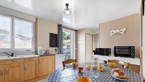 Una cocina con armarios de madera, una mesa de comedor con mantel estampado de lunares y un microondas.