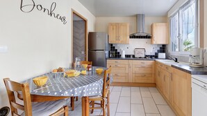 Una cocina con armarios de madera, un refrigerador de acero inoxidable, una mesa de comedor con sillas y una ventana con vistas.