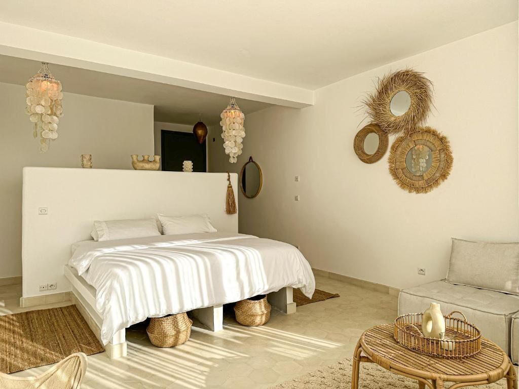 A bedroom with a bed, a sofa, a wicker coffee table, and decorative wall art.