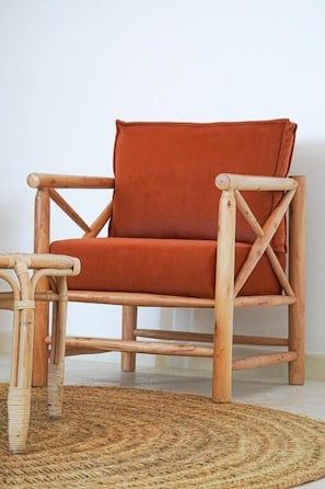 A wicker chair with a cushion, a woven rug, and a plain wall. - Villa Le Belvedere (Tangier)