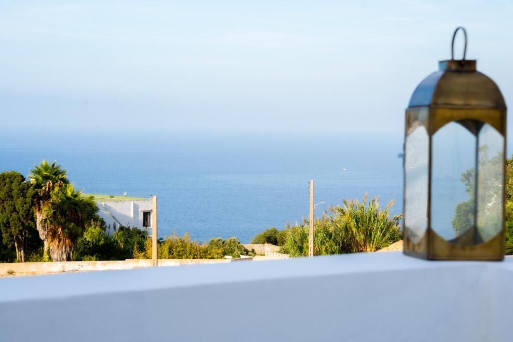 A view of the sea from a balcony with a lantern on a table.