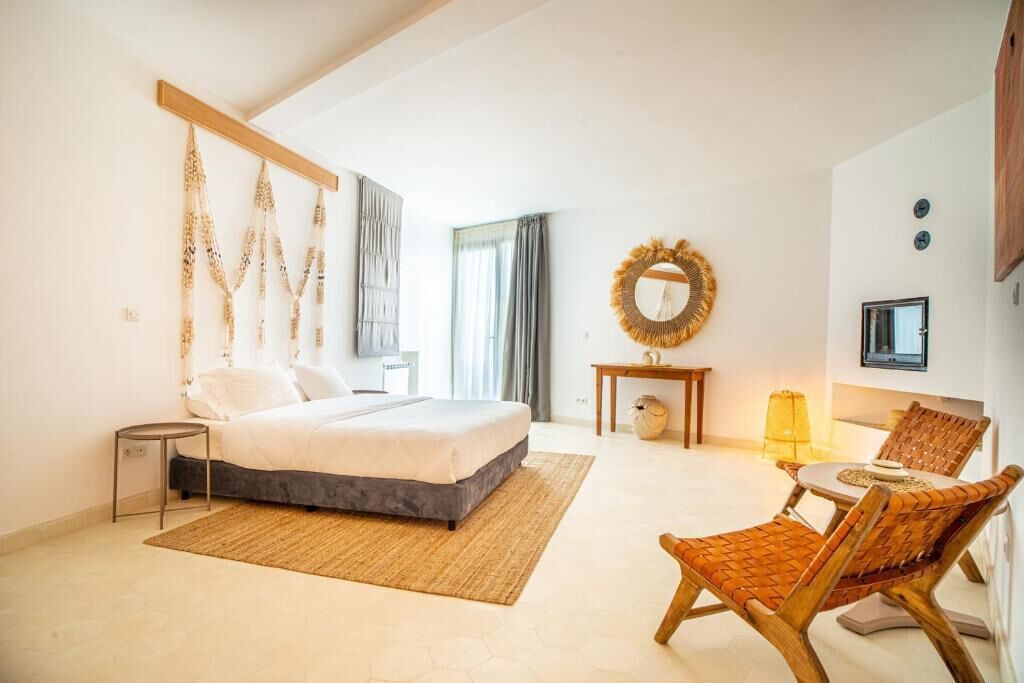 A bedroom with a bed, bedside table, lamp, chair, and a decorative mirror.
