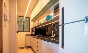 Eine moderne Küche mit weißen Schränken, einer schwarzen Arbeitsplatte und einem Edelstahl-Kühlschrank.