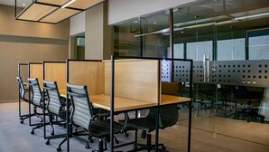 Un bureau moderne avec des cloisons, des chaises ergonomiques et une paroi de séparation en verre.