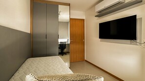 Ein Schlafzimmer mit einem Bett, einem Fernseher, einer Klimaanlage und einem Kleiderschrank.