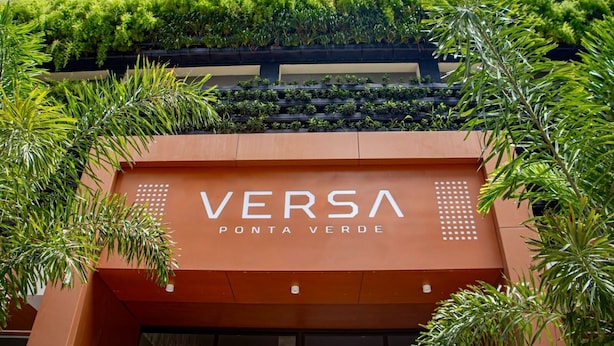 Une devanture de magasin portant l’enseigne « VERSA PONTA VERDE », entourée d’une végétation luxuriante.