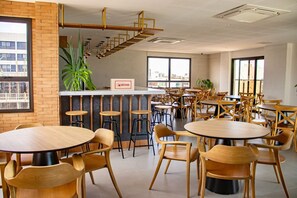 Een modern café met ronde tafels en stoelen, een bakstenen muur en een trap.