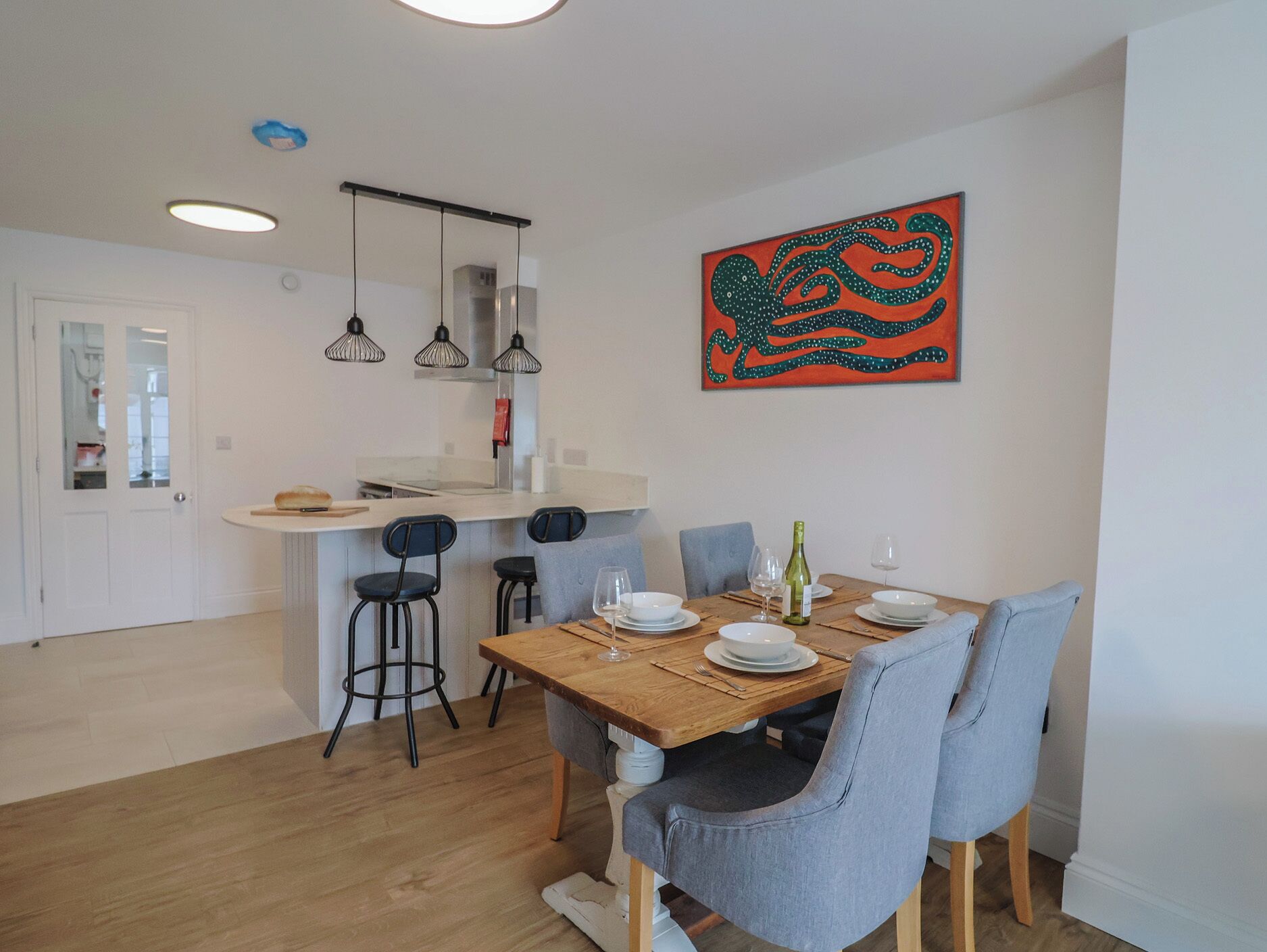 Un comedor con una mesa de madera, sillas y un cuadro en la pared.