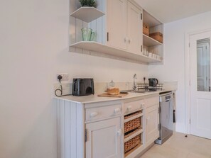 A kitchen with a toaster, a bread loaf, a coffee maker, and a dish rack. - Flat 1 Harley House (Sidmouth)