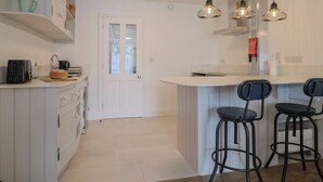 Una cocina moderna con una isla central, taburetes de bar e iluminación colgante.