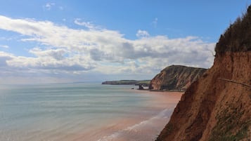 A coastal landscape with cliffs, a beach, and a clear sky.