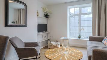 Una sala de estar con sofá, sillón, televisor y un tapete redondo.