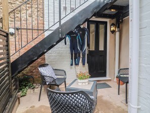 A staircase leading to a door, outdoor seating with cushions, and a potted plant. - Flat 1 Harley House (Sidmouth)