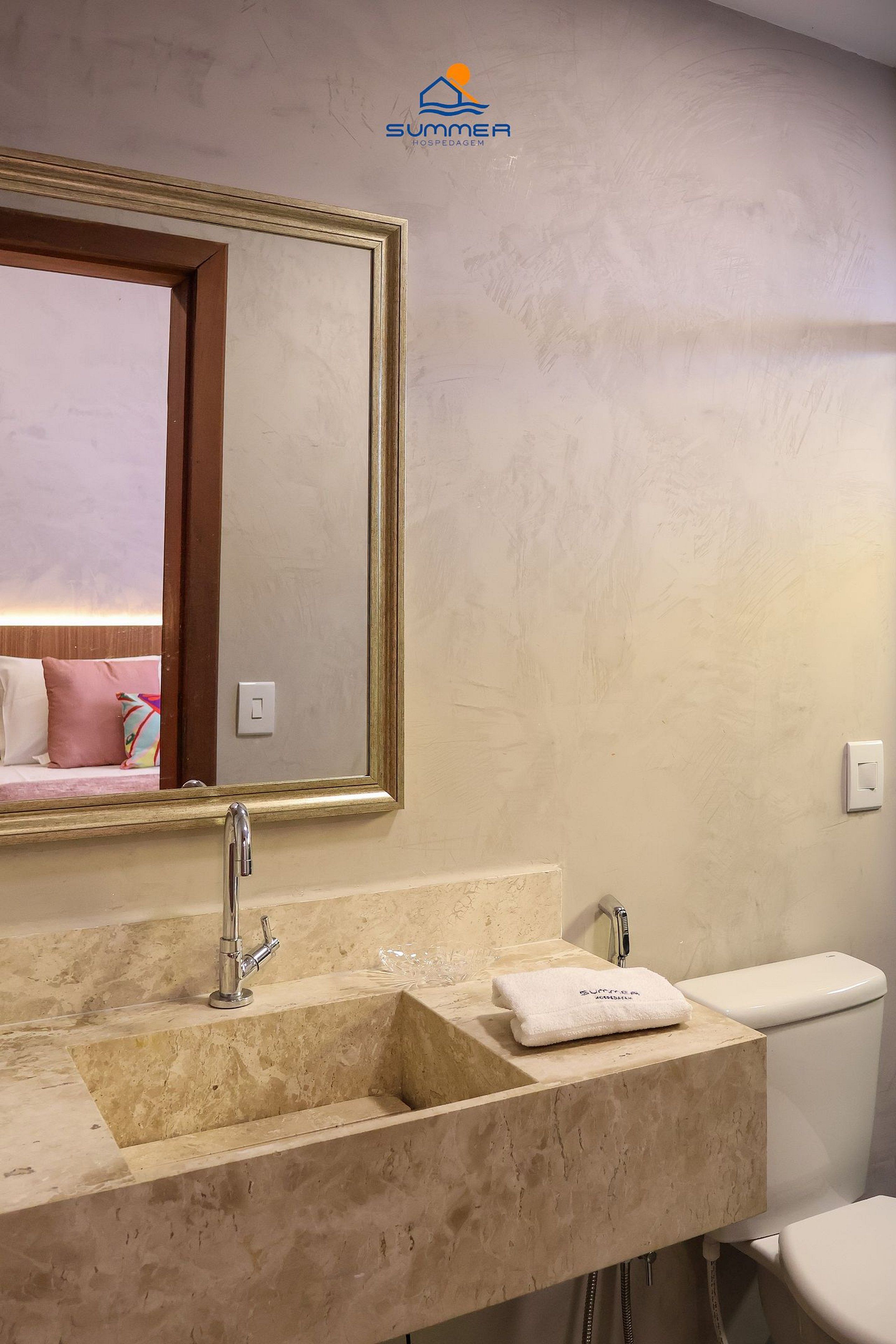 A bathroom with a beige sink, a mirror, a towel, and a toilet.