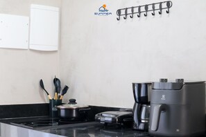 Una cocina equipada con estufa, cafetera y utensilios.