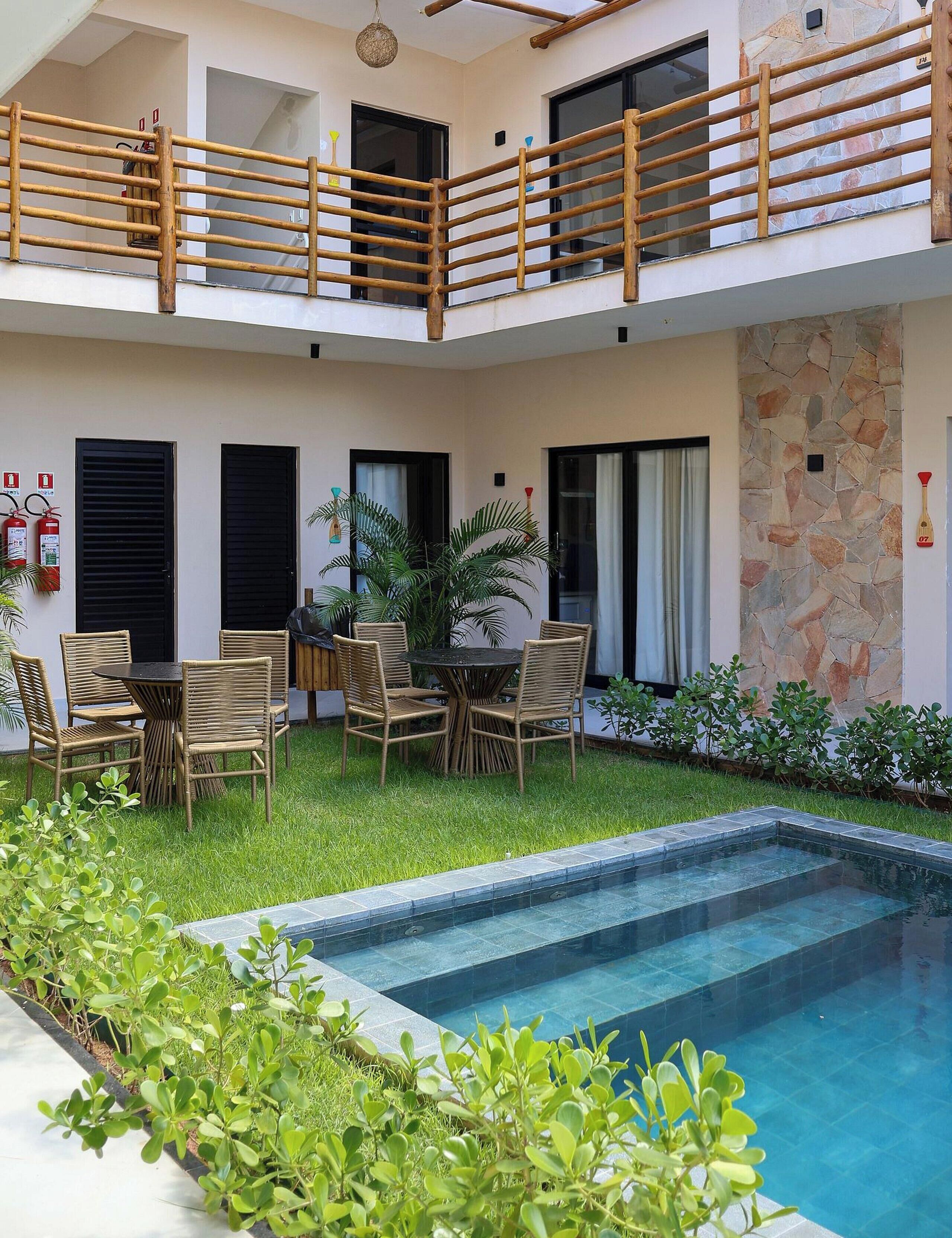 A two-story building with a pool, outdoor seating, and a stone wall.