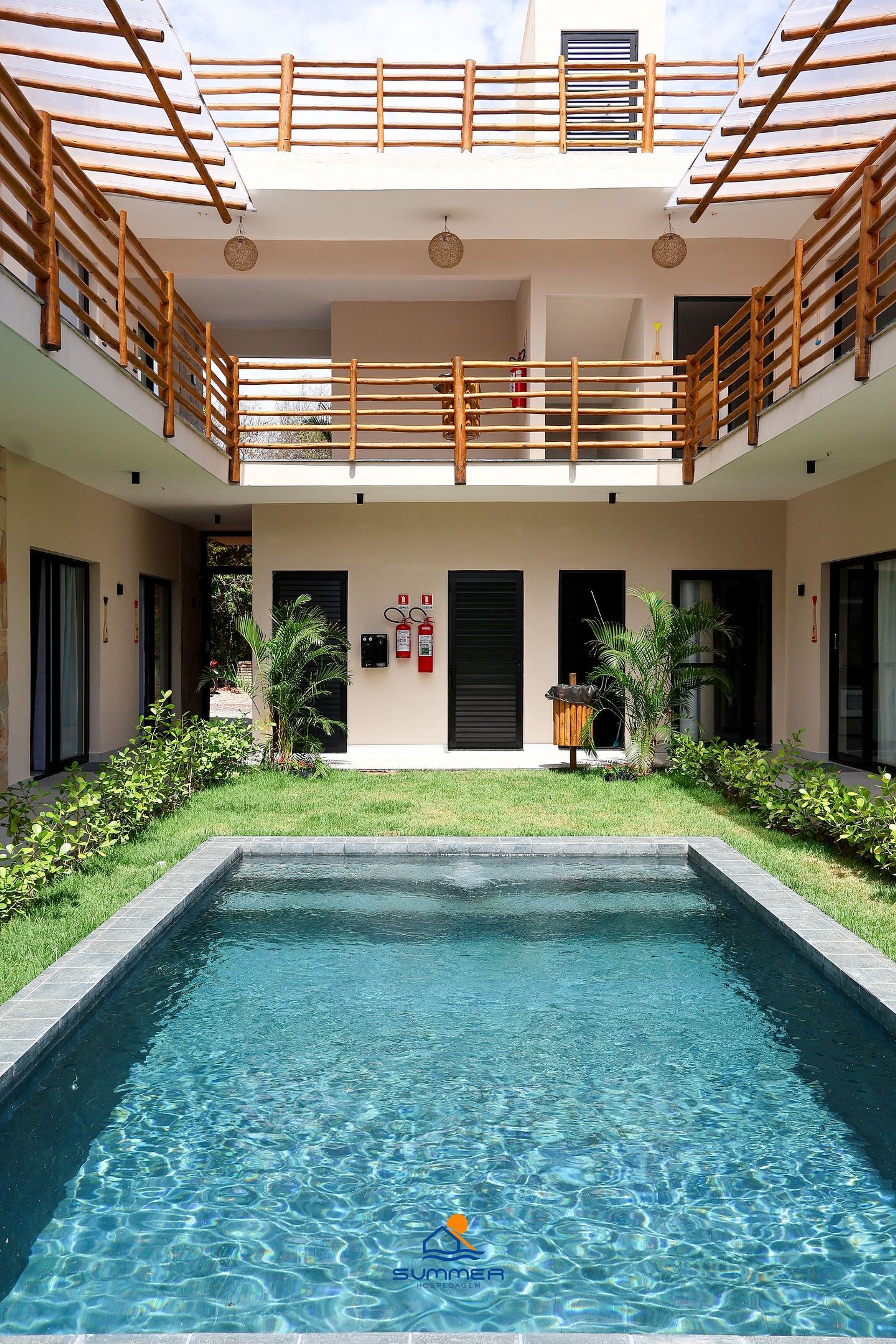 A swimming pool with a wooden deck and a covered upper level with a railing.
