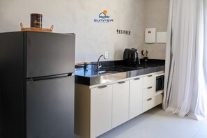 A modern kitchen with a refrigerator, a sink, and a coffee maker. - Condominio Petit (TIBAU DO SUL)