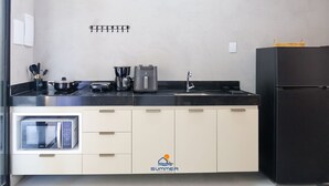 A modern kitchen with a microwave, toaster, kettle, and sink. - Condominio Petit (TIBAU DO SUL)