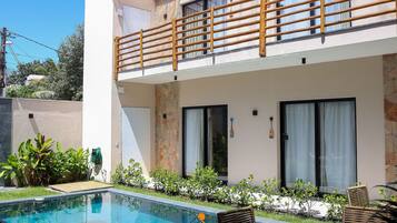 A modern hotel with a pool, outdoor seating, and a balcony.
