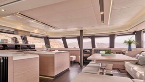 A modern interior with a central dining area, seating arrangements, and a view through large windows. - Floating Villa: Yacht Vacation with Captain & Chef - 10 Guests - 66 Ft (Άλιμος)