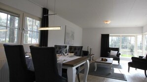 A dining area with a table set for four, a sofa, and a view of the outdoors. - Holiday Home in Otterlo With Terrace (Otterlo)