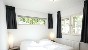A bedroom with a bed, two bedside tables, a window, and a radiator. - Holiday Home in Otterlo With Terrace (Otterlo)