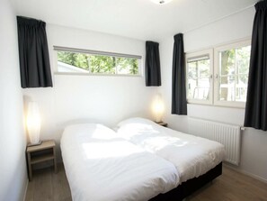 Ein Schlafzimmer mit einem Bett, zwei Nachttischen, einem Fenster und einer Heizung.