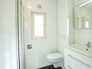 Ein modernes Badezimmer mit Toilette, Waschbecken und Spiegel.