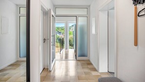 Un couloir donnant sur un balcon, une porte avec une poignée et un crochet fixé au mur.