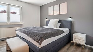 Une chambre moderne avec un grand lit, des lampes de chevet, une fenêtre et un radiateur.