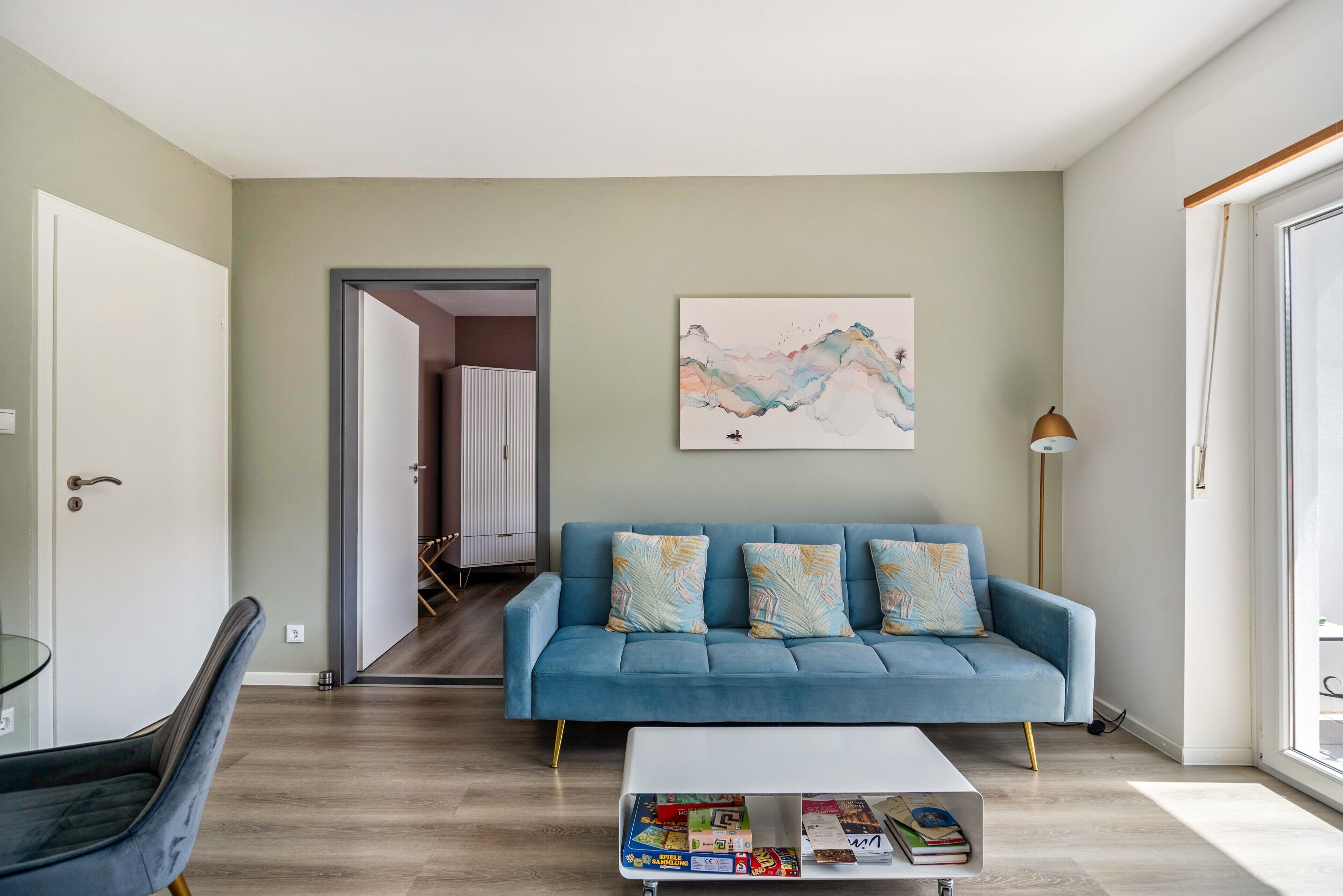 Una sala de estar moderna con un sofá azul, una mesa de centro y un cuadro en la pared.