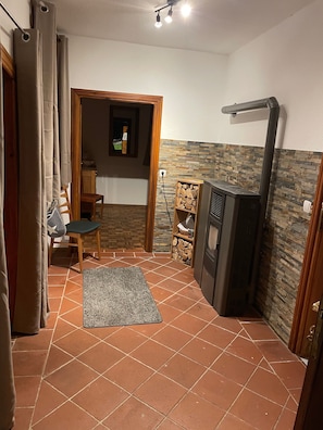 Ein Zimmer mit Fliesenboden, Kamin, einem kleinen Tisch mit Stühlen und einem Fenster.
