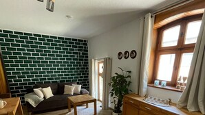 En stue med en væg i murstensmønster, en træsofa, et sofabord, et træskab og et vindue med gardiner.