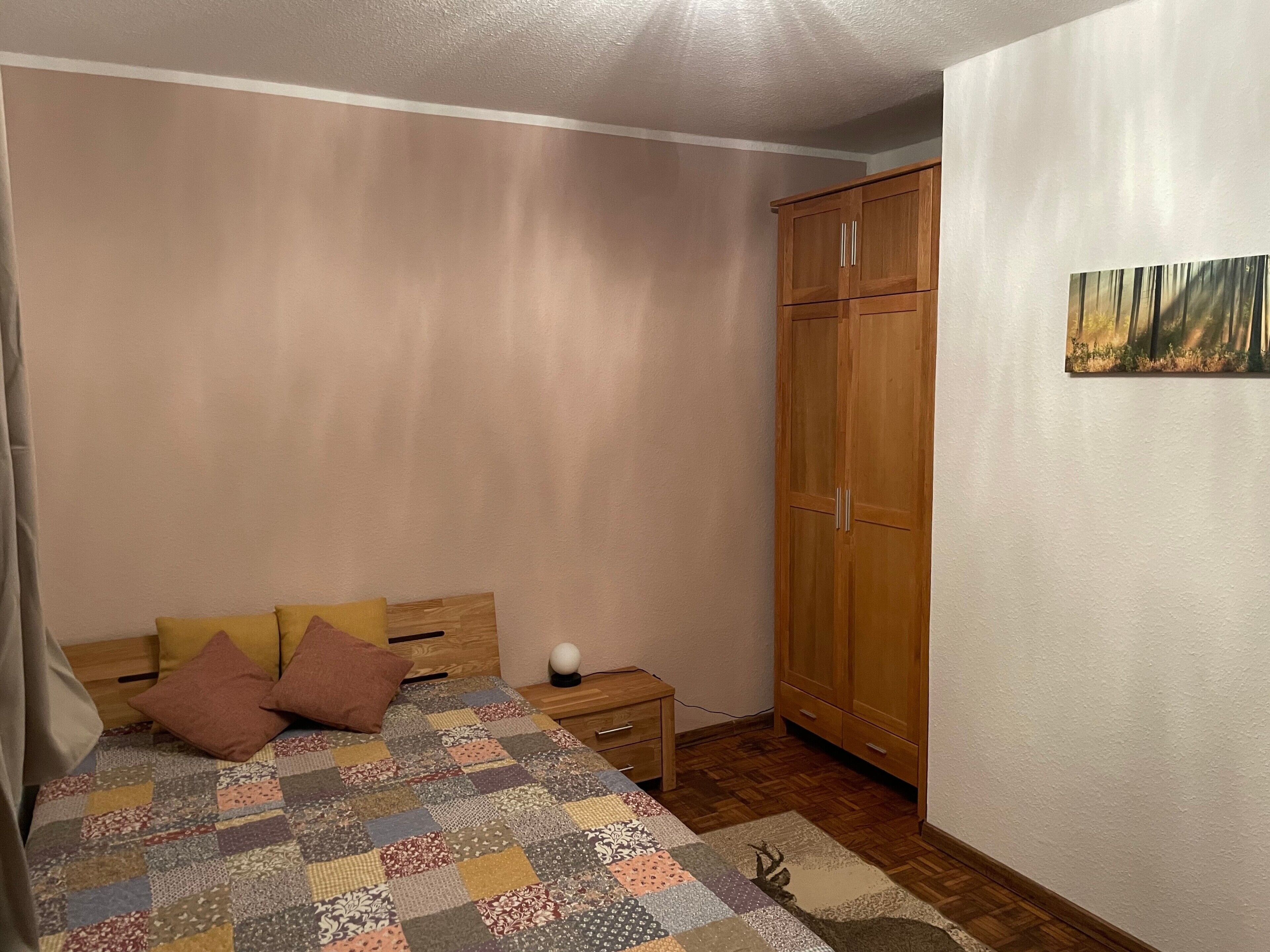 Une chambre à coucher avec un lit en bois, une armoire en bois et une petite table de chevet.