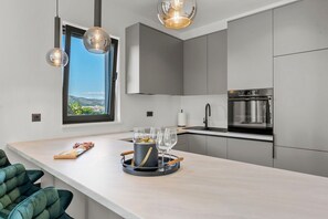 Eine moderne Küche mit großem Fenster, Backofen und Essbereich mit heller Arbeitsplatte.