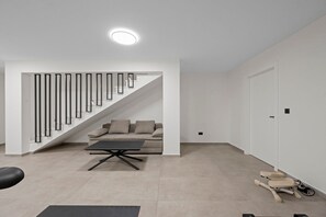 Ein modernes Wohnzimmer mit Treppe, einer Couch, einem Couchtisch und einem Paar Rollschuhen.