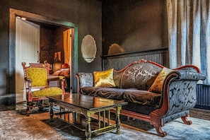A room with a dark-colored sofa, a wooden coffee table, and a patterned armchair. - Frenchmen - New Orleans (New Orleans)