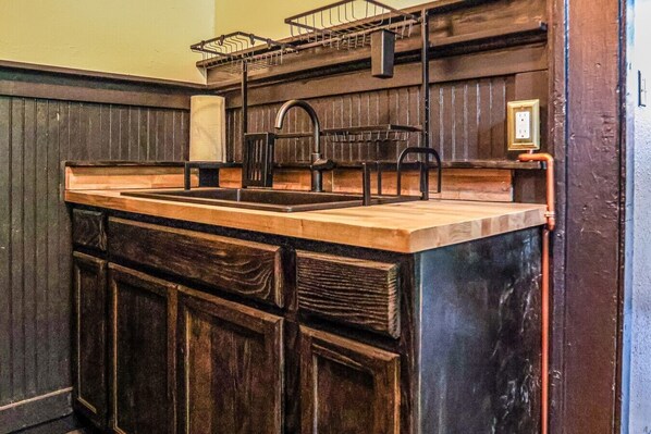 A kitchen with a wooden countertop, a sink, and a metal rack. - Frenchmen - New Orleans (New Orleans)