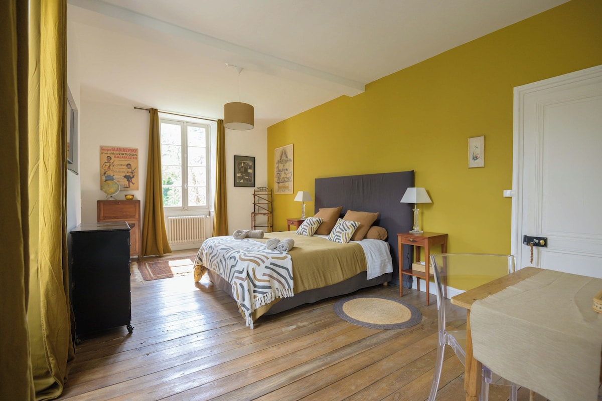 Een slaapkamer met een bed, nachtkastjes, een lamp, een kaptafel en een raam met gordijnen.
