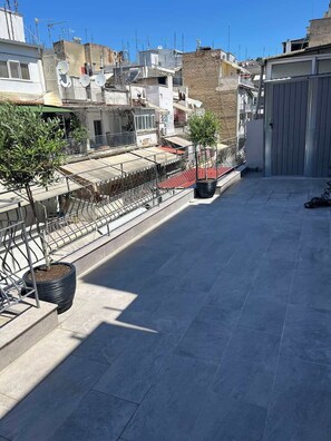 Eine Dachterrasse mit Metallgeländer, Blumentöpfen und Blick auf die umliegenden Gebäude.