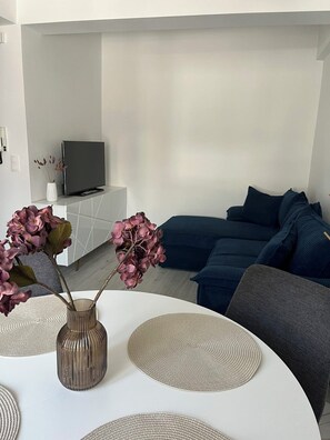 Ein modernes Wohnzimmer mit einer Couch, einem Fernseher und Zimmerpflanzen.
